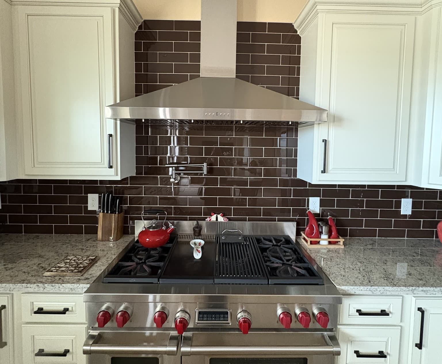 Completed kitchen range wall with stove, microwave, cabinetry, and backsplash